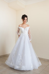 Fototapeta premium Beautiful bride wearing fashion wedding dress with feathers with luxury delight make-up and hairstyle studio indoor photo shoot