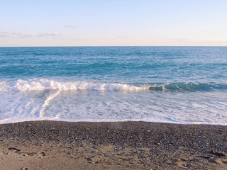 Genova, Italy - 03/08/2019: An amazing caption of small waves and beautiful sunset with an incredible reflection over the sea and some coloured clouds in winter days, and some black and white photos.