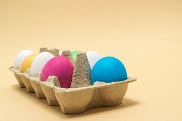 Colorful Easter eggs in tray  on beige.