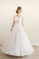 Fototapeta premium Beautiful bride wearing fashion wedding dress with feathers with luxury delight make-up and hairstyle, studio indoor photo shoot