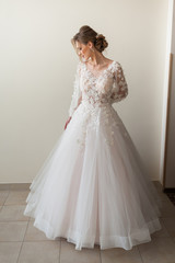 Fototapeta premium Beautiful bride wearing fashion wedding dress with feathers with luxury delight make-up and hairstyle, studio indoor photo shoot
