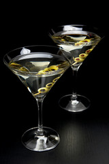 Martini drinks with olives isolated on black table