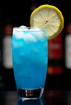 Blue lagoon cocktail with slice of lemon isolated on black in a bar