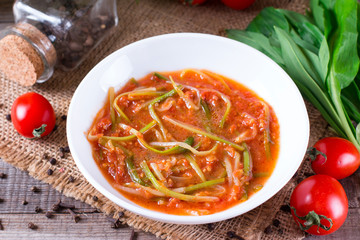 Ramson or wild garlic leaves in tomato sauce in a plate
