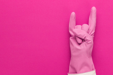 hand in pink protective glove shows horns gesture. cool cleaning service concept with copy space
