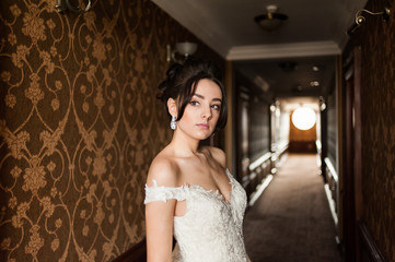 Beauty portrait of bride wearing fashion wedding dress with feathers with luxury delight make-up and hairstyle, studio indoor photo.