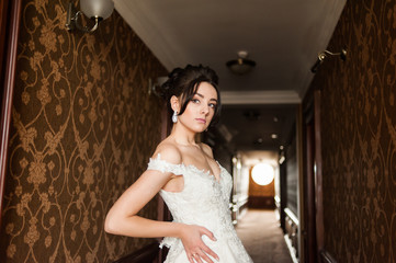 Beauty portrait of bride wearing fashion wedding dress with feathers with luxury delight make-up and hairstyle, studio indoor photo.
