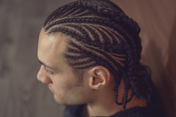 male hairstyle close-up braids, hair braided, pensive look, man portrait