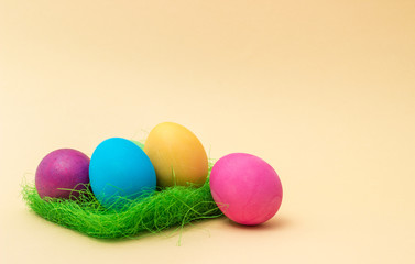 Colorful Easter eggs on grass and beige background. four eggs.
