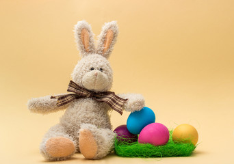 Handmade Bunny and Easter Colored Eggs. Beige background. 