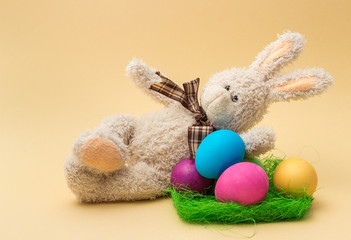 Handmade Bunny and Easter Colored Eggs. Beige background. 