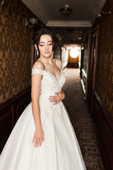 Beauty portrait of bride wearing fashion wedding dress with feathers with luxury delight make-up and hairstyle, studio indoor photo.