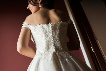 Beauty portrait of bride wearing fashion wedding dress with feathers with luxury delight make-up and hairstyle, studio indoor photo.