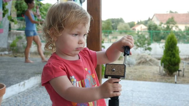 Baby playing with a monopod, kid is walking and exploring the monopod
