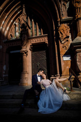 young beautiful couple bride and groom walk in the city on the background of the church and smile the bride in a beautiful dress the groom dressed stylishly