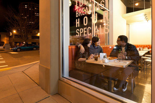 Multiethnic group of friends people customers having fun together dining out in cafe restaurant at night