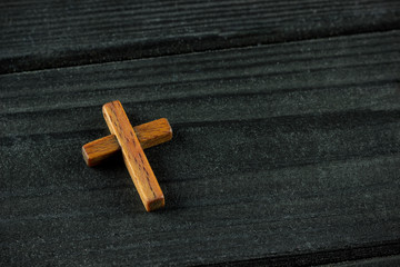 wooden cross on a dark wooden background, space