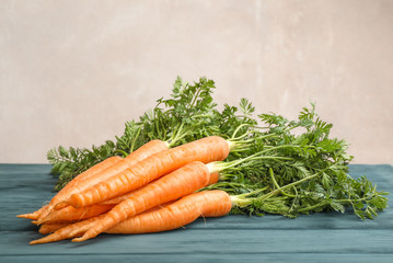 Ripe carrots on wooden table against light background, space for text