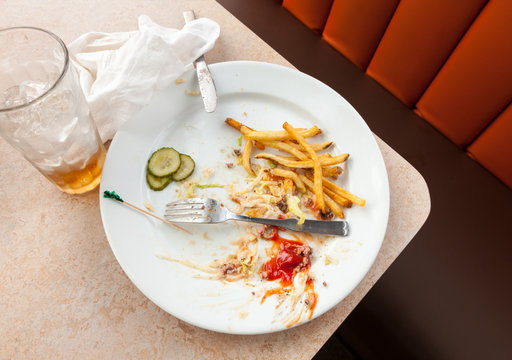 Remains of a satisfying meal on empty plate. Dirty dishes in restaurant cafe diner.