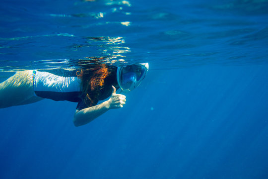 Red hair woman snorkeling undersea. Snorkel show thumb up underwater. Underwater photo of woman snorkeling
