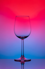 Wine glass on a high and thin stalk on a colored background.