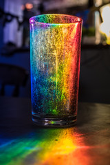 the side of an old used glass tumbler illuminated by rainbow light