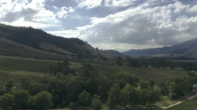 Aerial pan with greanery in front clouds and mountain behind