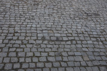 gray stone texture of old square paving tiles on the road