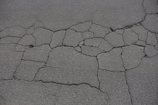gray stone background of old asphalt in cracks in the road