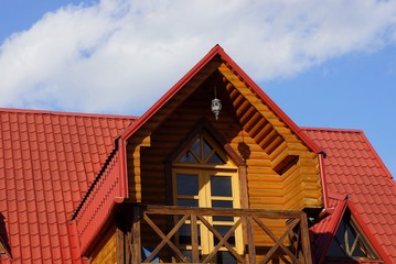 brown wooden balcony with door and red tiles on the roof against the sky
