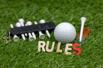 Rules of golf with golf ball and sign on green grass 