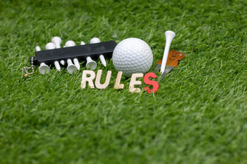 Rules of golf with golf ball and sign on green grass 
