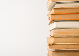 A stack of old books. Yellow frayed pages. Worn damaged book covers. Book store or e-books.