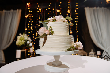 Beautiful two-tier delicious white wedding cake decorated with pastel pink flowers