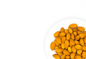 Almond on plate on white background with place for text, top view photo. Tasty healthy snack. Scattered nut on table