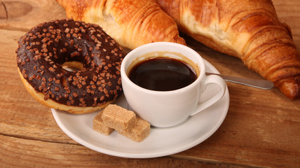 Coffee white cup, croissants on wooden table and roasted coffee beans. Breakfast concept