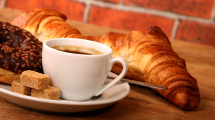 Coffee white cup, croissants on wooden table and roasted coffee beans. Breakfast concept