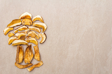 Dried mushrooms boletus edulis (penny bun, cep, porcino). Ingredient for vegetarian (vegan) food. On a stone background, laid out in the shape of a mushroom, top view, copy space.