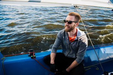 Captain of the yacht wearing sunglasses in a race on a river or sea at sunset