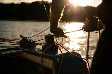 Silhouette of a sailors hands on a winch rope on a sailboat on a sunset. Shot with a selective...