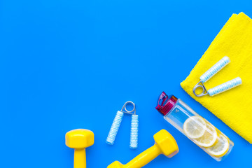 Sport with bars, towel, water and wrist builder on blue background top view space for text