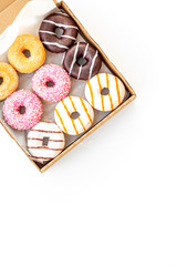 Glazed decorated donuts in box for sweet break on white background flat lay copy space