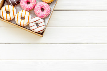 Modern design with donuts in box on white wooden background top view space for text