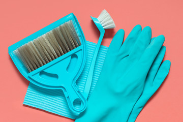 A set of blue tools for spring cleaning on the living coral background : rubber gloves, a broom and dustpan, brush for washing dishes, cloth for dust