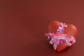 Valentine's Day heart bound and tied by pink and purple ribbon on red background