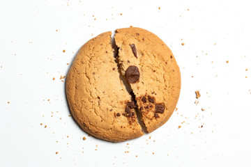 Chocolate chip cookie broken in half isolated on white surrounded by crumbs. Food baking design concept. Unhealthy snack junk food.