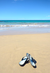 Fototapeta na wymiar Sandals on Tropical Hawaii Beach. Surf, beach and Sunny Blue Sky day. Big Island, Hawaii