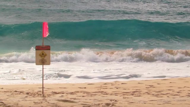 Slow motion ocean waves with warning signs strong current at Sandy Beach in Honolulu on the island of Oahu, Hawaii.
