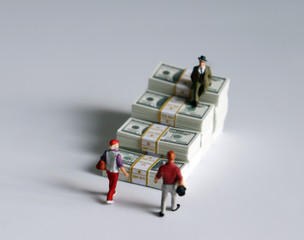 Miniature people and a pile of banknotes stacked in the shape of a staircase.
