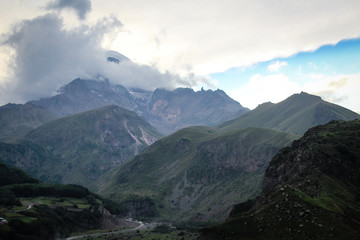Fototapeta premium The main Caucasian ridge. Georgia, Kazbegi village (Stepantsminda). Mount Kazbek. Mountains, summer, twilight. Beautiful, amazing sky. High mountains. Vacation, hike. christian Gergeti Trinity Church